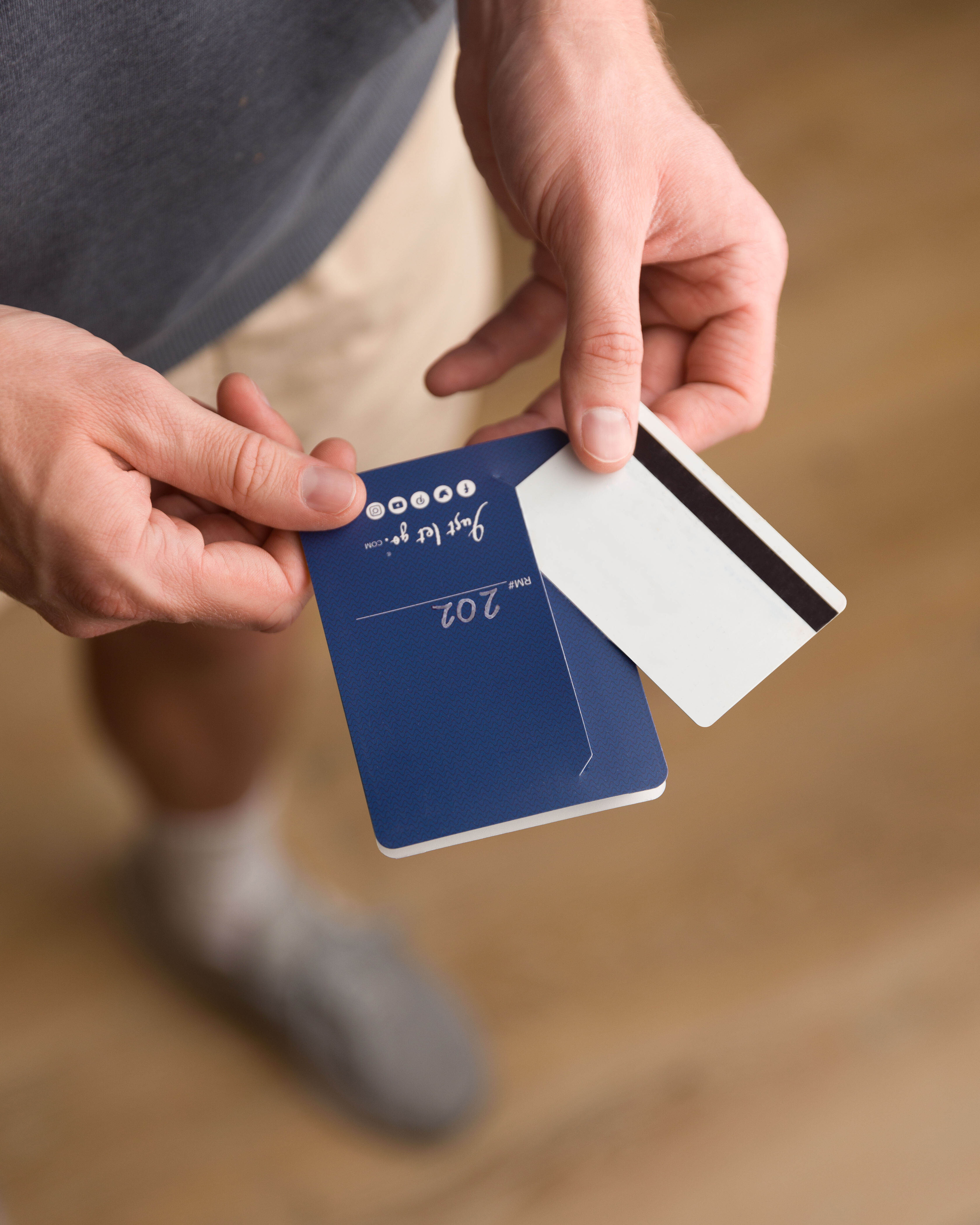 Close-up of a person holding a hotel key card and room information booklet, highlighting a seamless guest check-in experience. Ideal for showcasing digital hotel solutions like PocketMaps